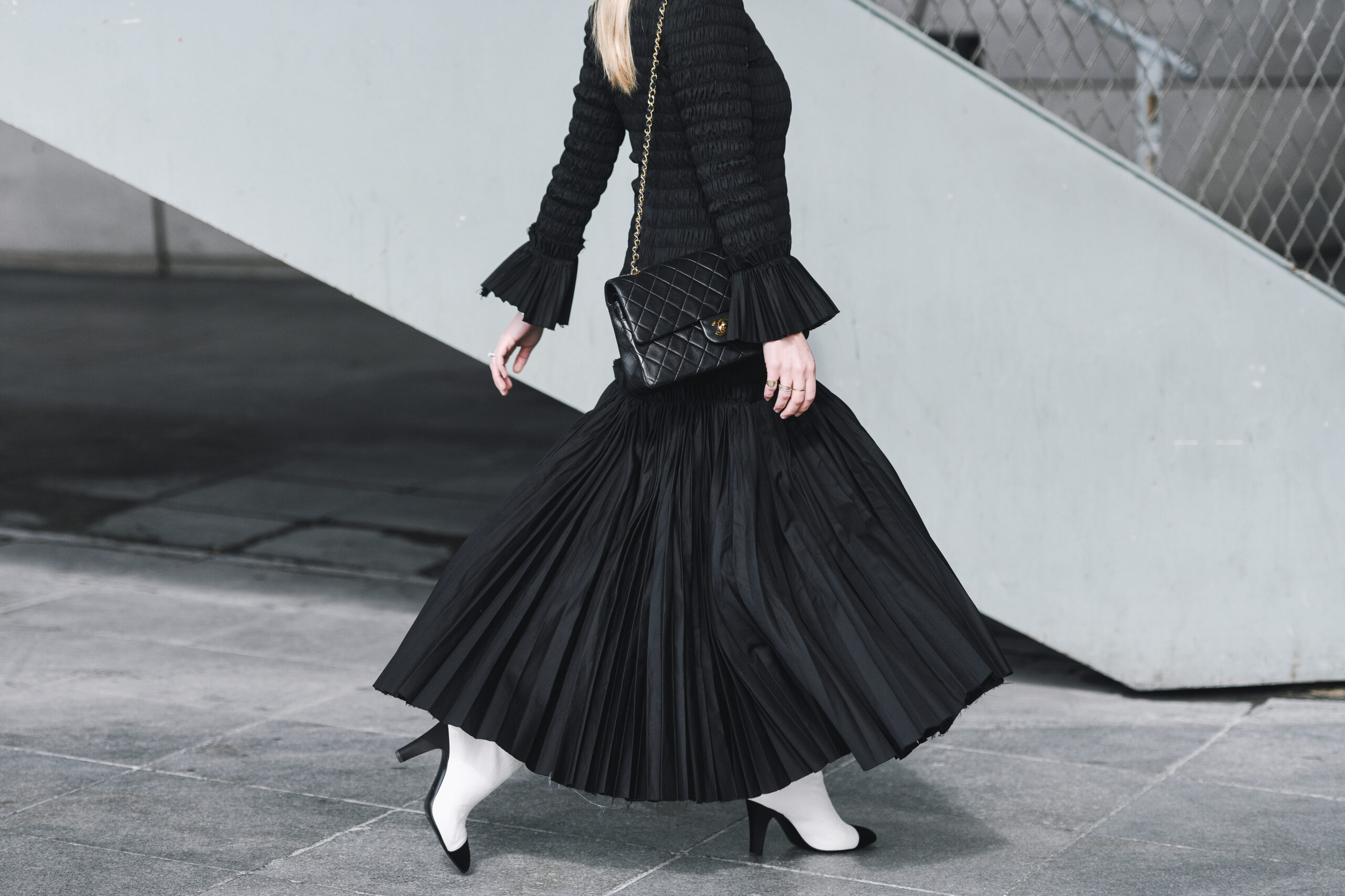 Woman alking in a black dress and white boots